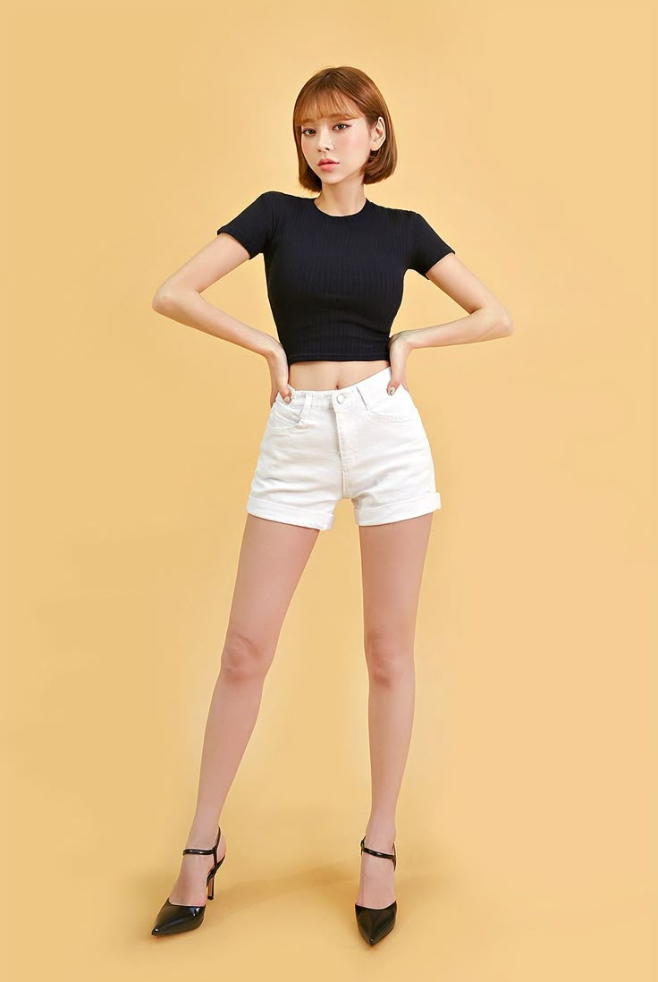 a woman in black shirt and white shorts standing with her hands on the hips while wearing high heeled shoes