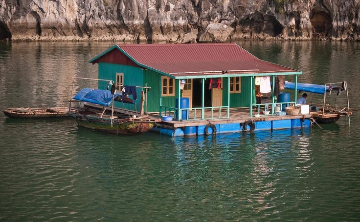 a houseboat floating on top of a body of water next to a rocky cliff