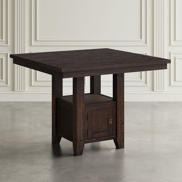 a wooden table sitting on top of a floor next to a white wall in an empty room