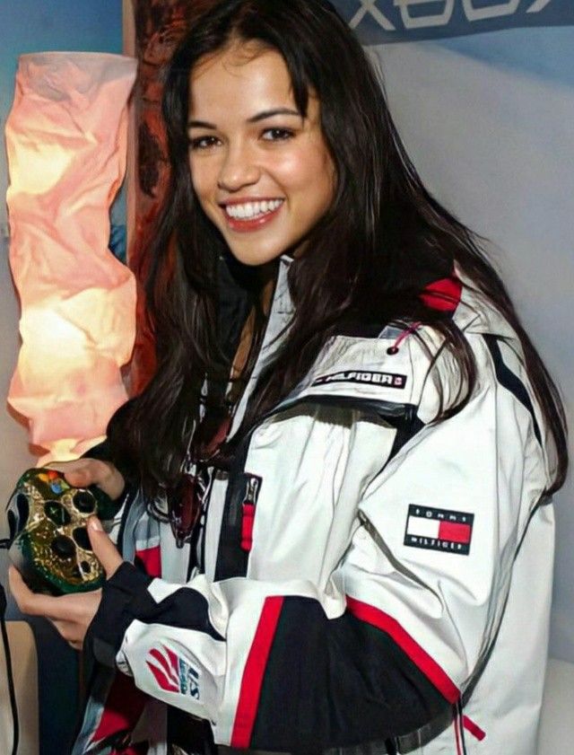 a woman holding a trophy in her right hand and smiling at the camera while standing next to a wall