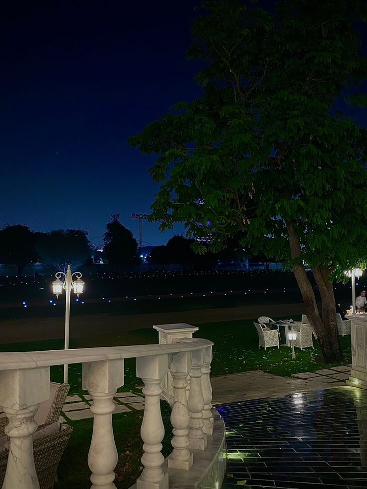 an empty park bench at night with lights on the benches and trees in the background