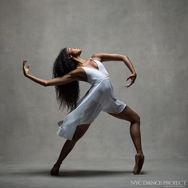 a woman in a white dress is dancing with her arms outstretched and legs spread out