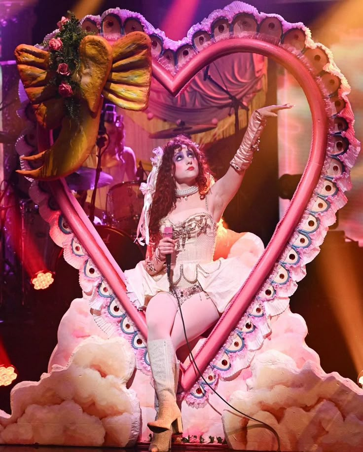 a woman is performing on stage in front of a heart