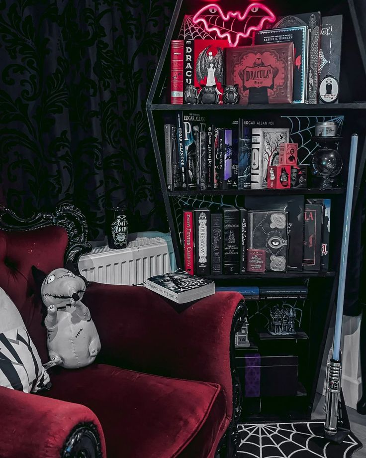 a red chair sitting in front of a book shelf filled with books and other items