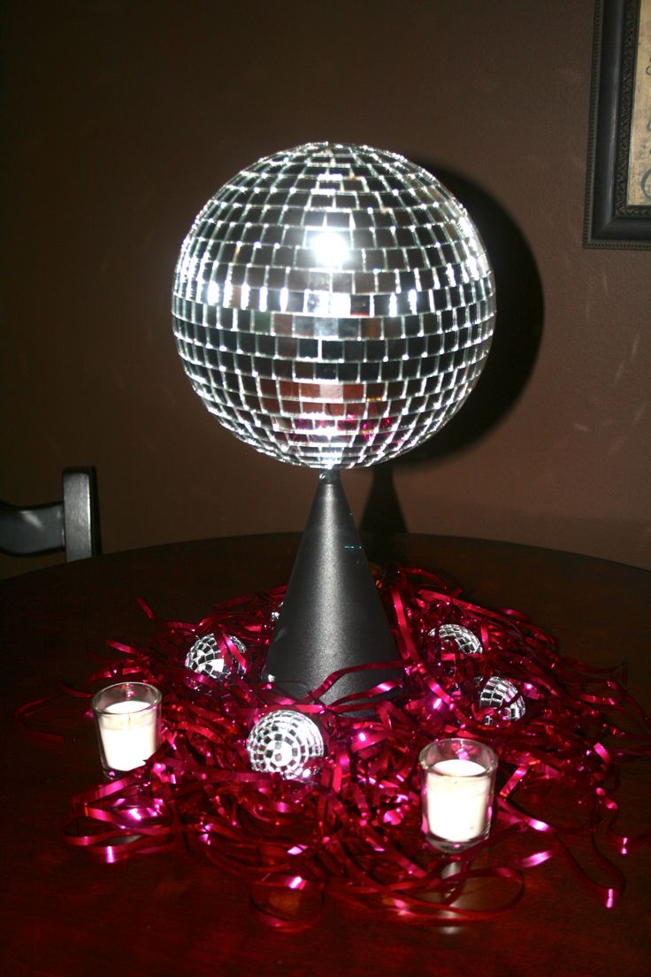 a disco ball sitting on top of a table next to some candles and confetti