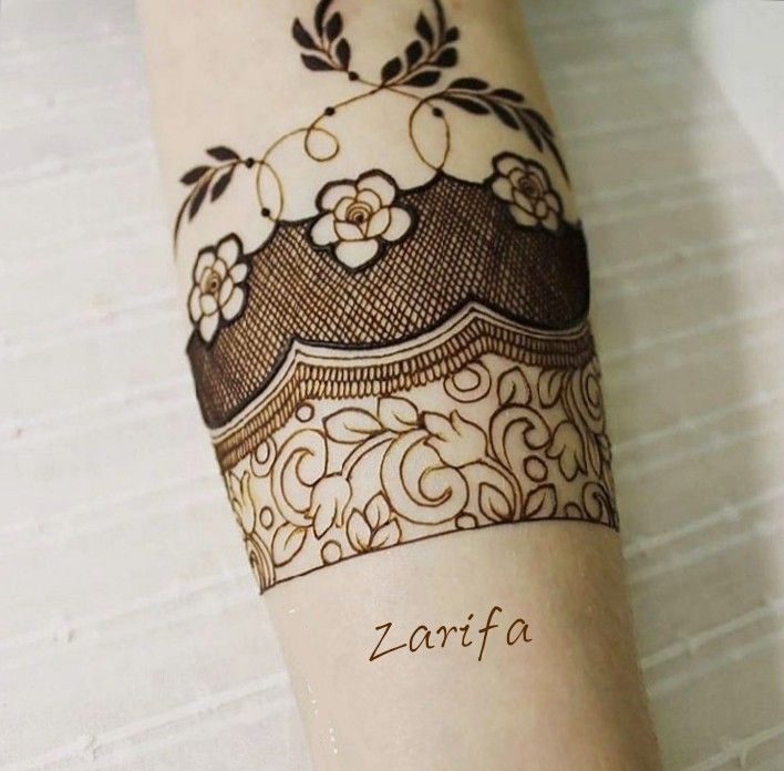 a woman's arm is decorated with hendix and flower designs on it