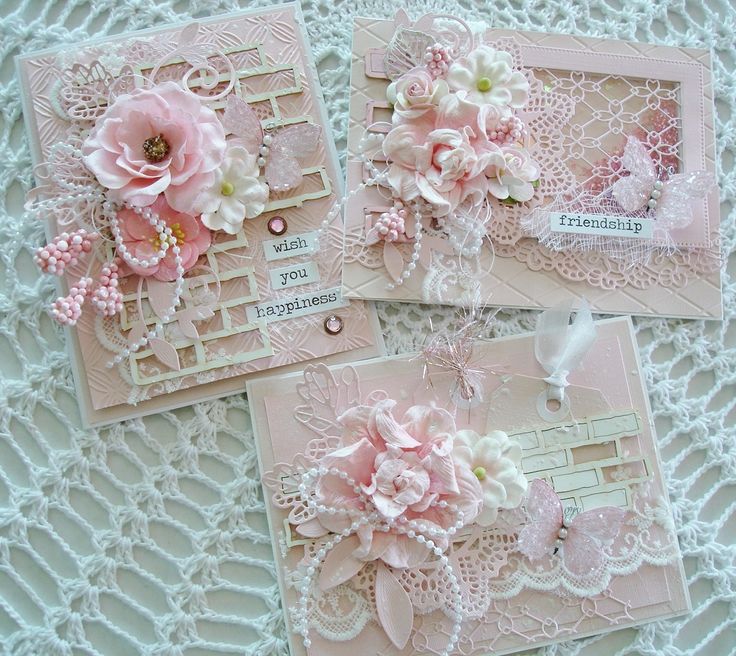 three cards with pink flowers and lace on them are laying on a white doily