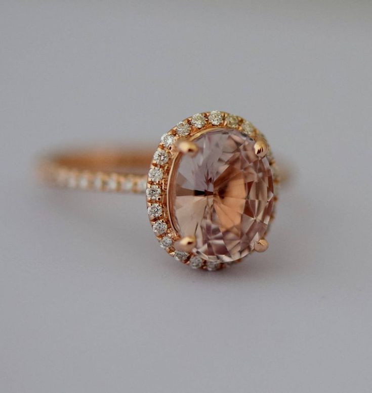 an engagement ring with a large pink stone surrounded by small white and yellow diamond accents