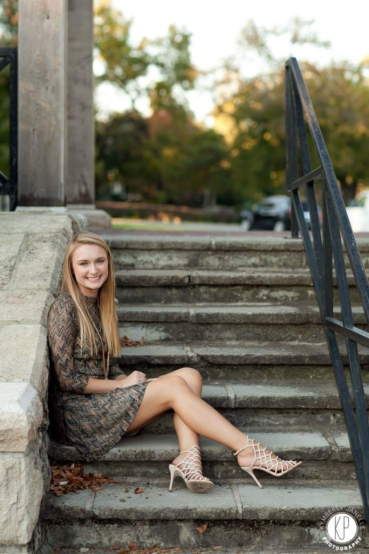 a woman sitting on steps with her legs crossed and wearing high heeled shoes, smiling at the camera