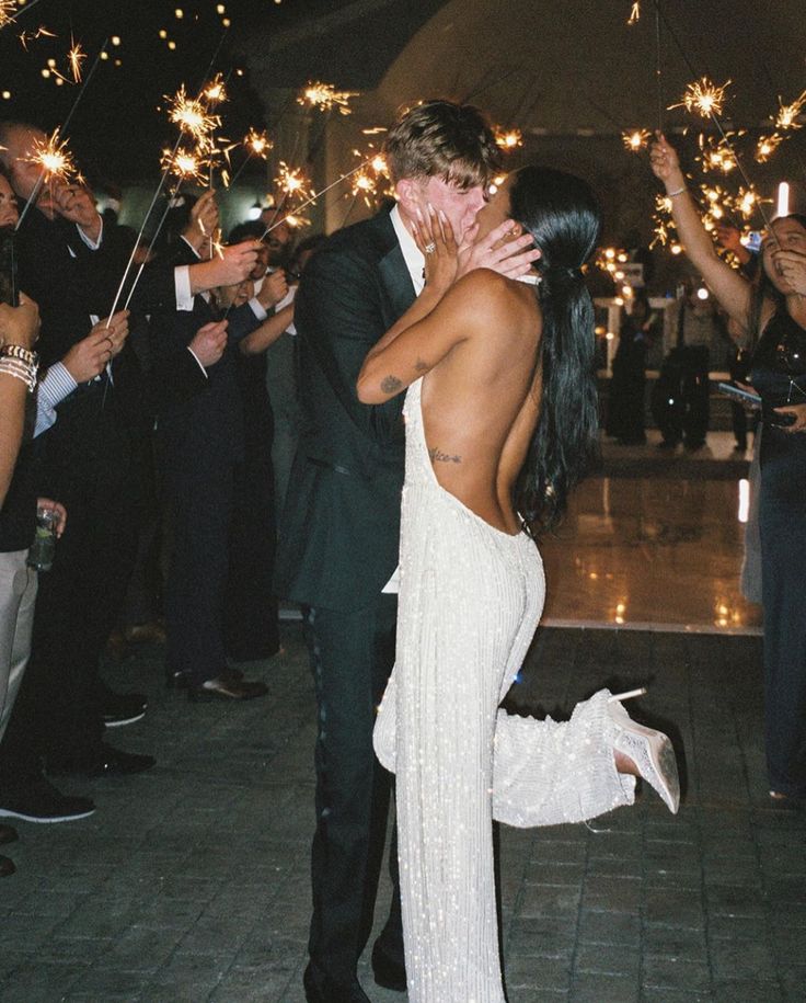 a bride and groom kissing in front of their guests with sparkler wands all around them