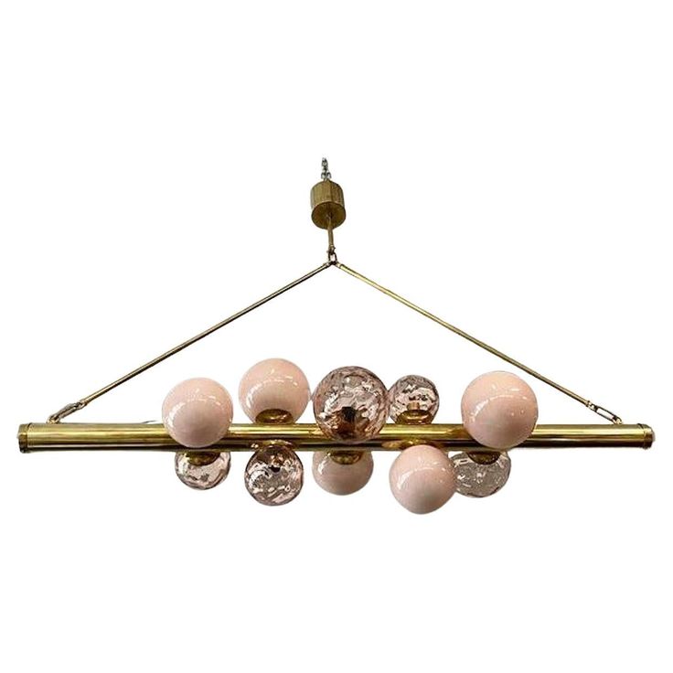 a chandelier with pink glass balls hanging from it's long brass frame