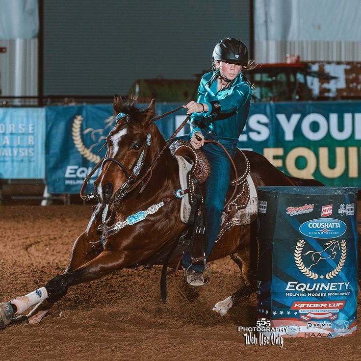 a woman riding on the back of a brown horse next to a barrel filled with liquid