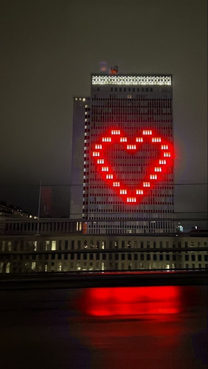 a large building with a lit up heart on it's side