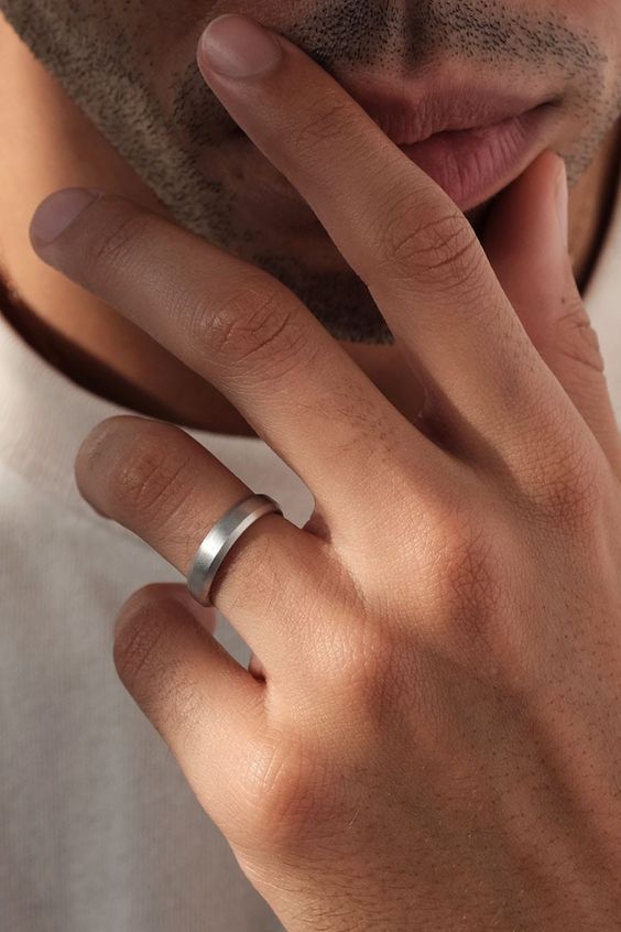 a close up of a person with a ring on his finger and wearing a white t - shirt