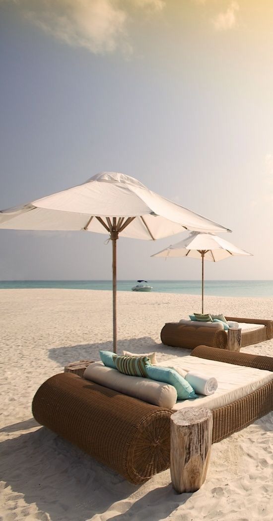 two lounge chairs with umbrellas on the beach