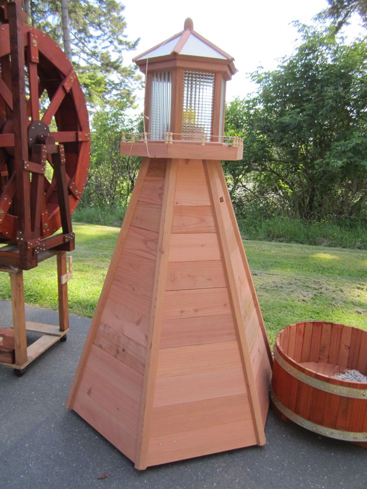 a wooden tower with a lantern on top next to a barrel and water spigot