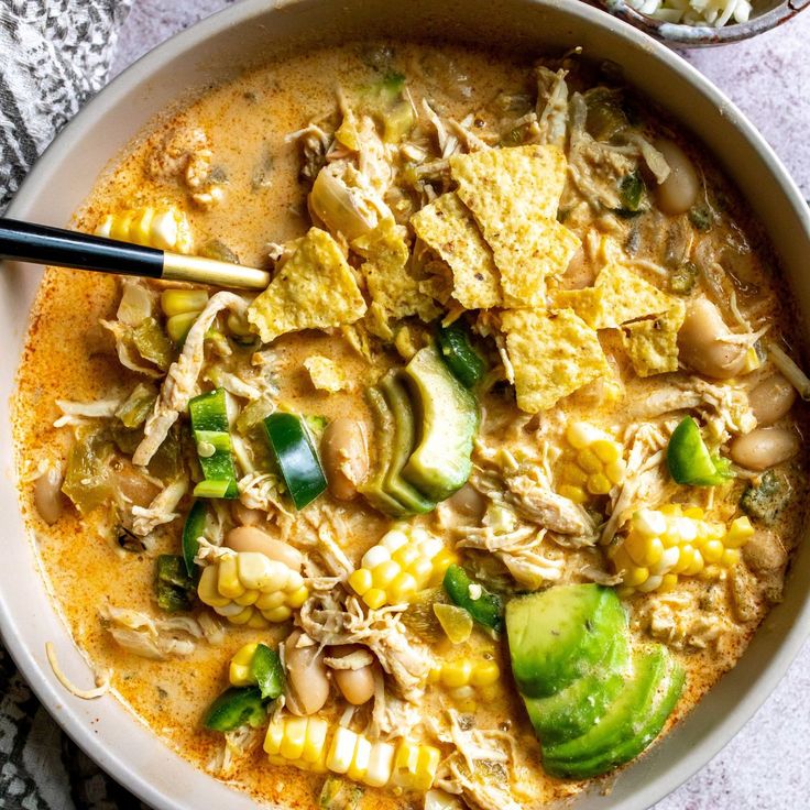 a bowl of white bean chili with chicken and tortilla chips on the side