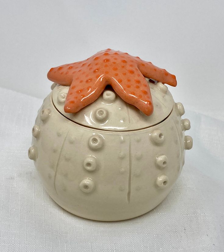 an orange starfish on top of a white ceramic container