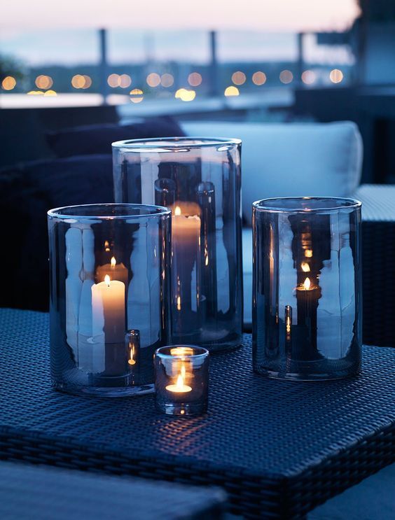 three glass vases with candles in them sitting on a table next to each other