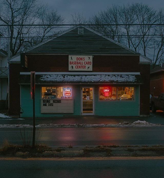 a donut shop is lit up at night in the winter with snow on the ground