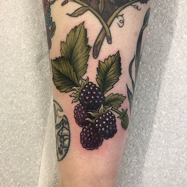 a close up of a person's leg with tattoos on it and fruit in the background