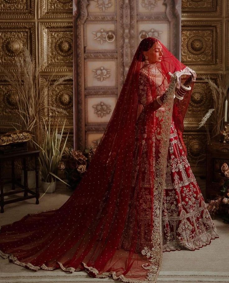 a woman wearing a red bridal gown and veil