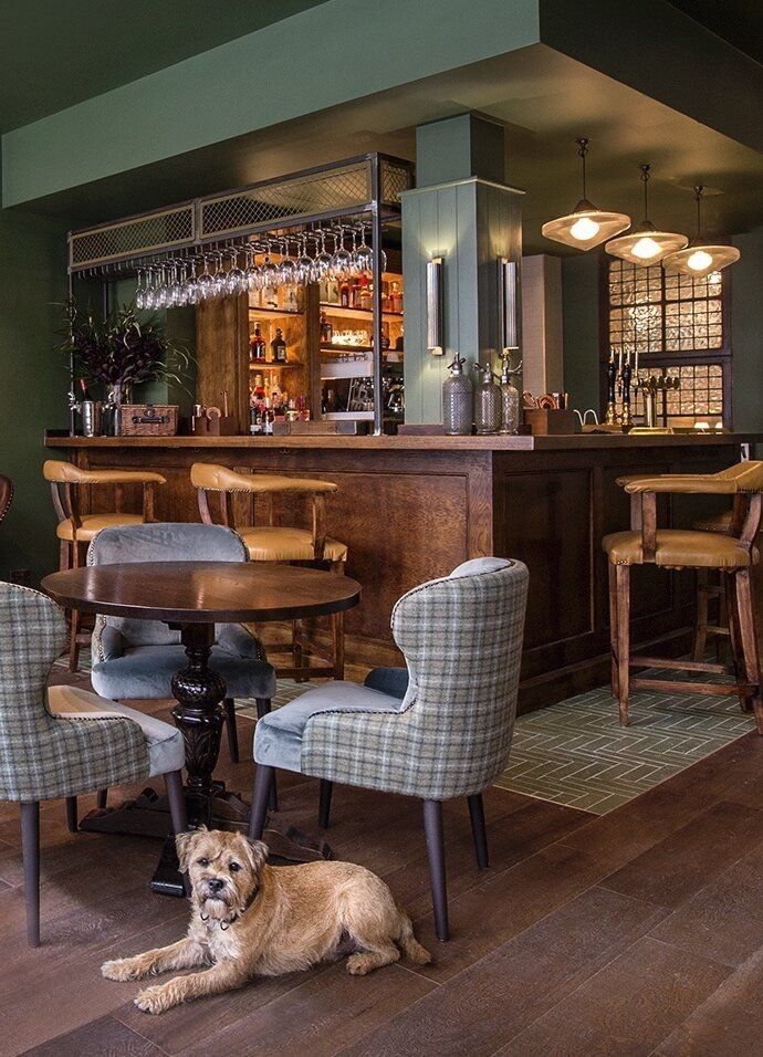 a dog laying on the floor in front of a table with chairs and a bar