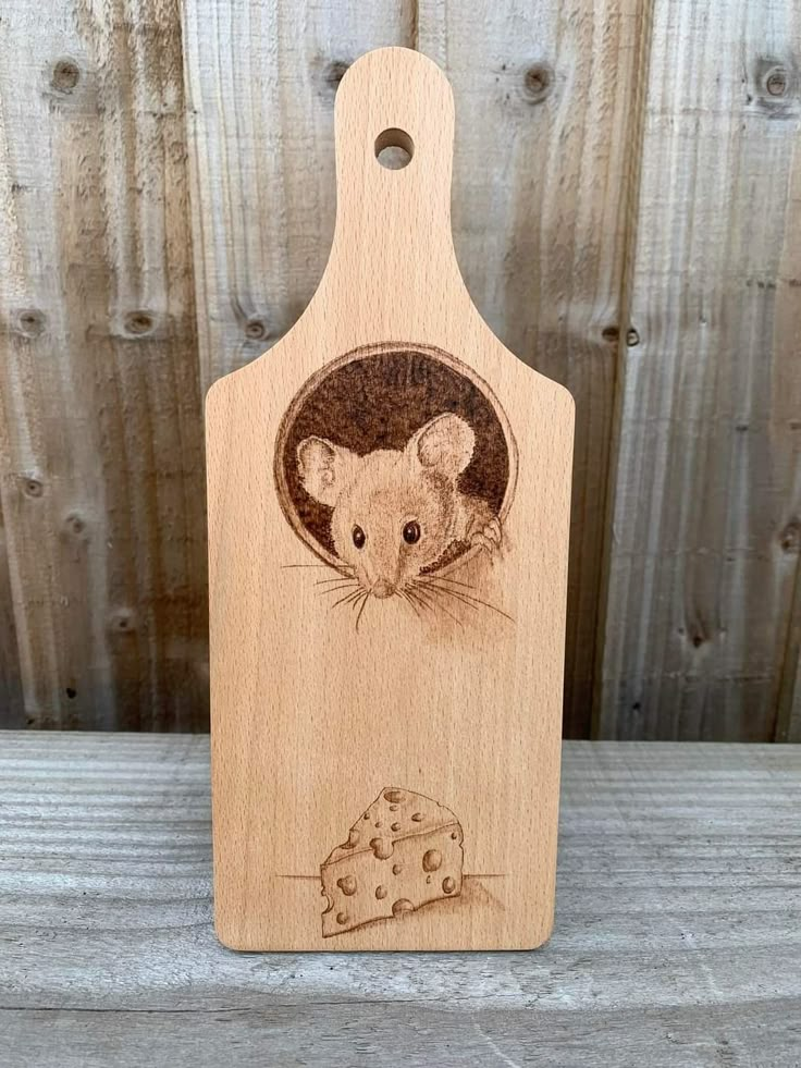 a wooden cutting board with an image of a mouse holding a piece of cheese on it