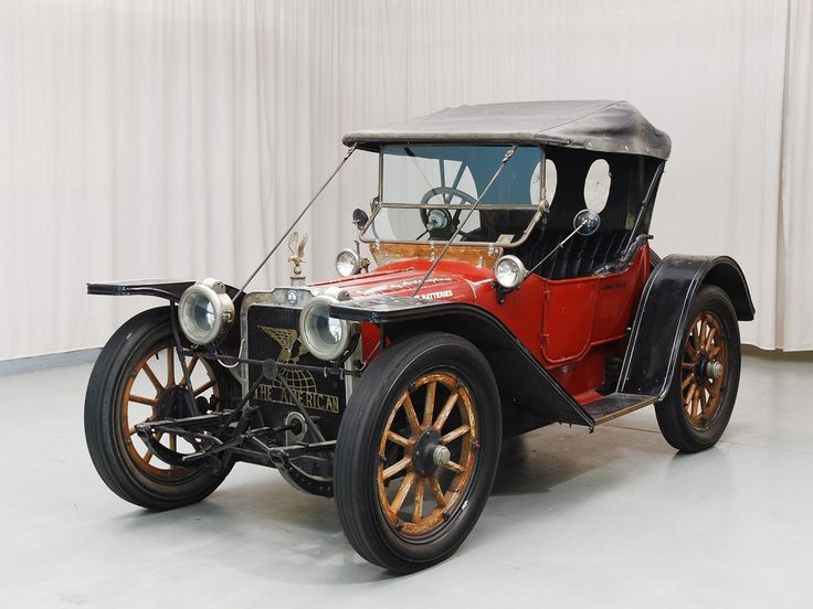 an old fashioned car is parked on the floor in front of a curtained wall