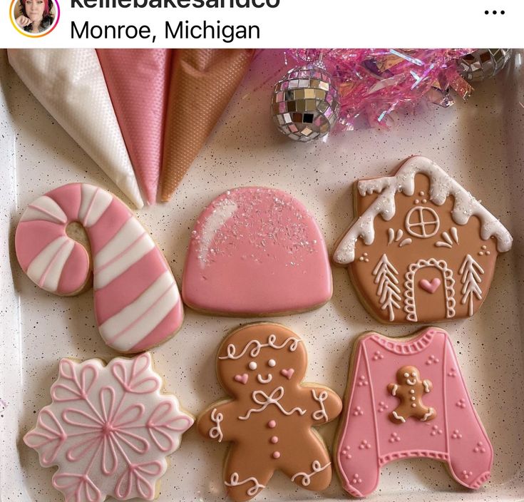 decorated cookies in a box with pink and white frosting on them, including gingerbreads