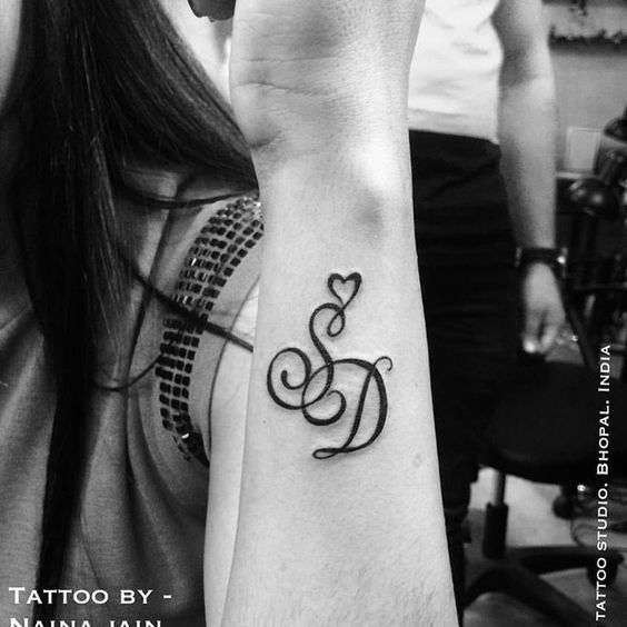 a woman's arm with a tattoo on it that has the letter d and a heart