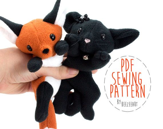 a hand holding two small stuffed animals in it's left hand, one black and one orange