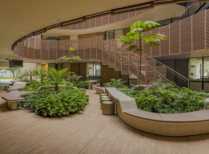 the interior of a large building with many plants and benches in front of stairs leading up to an upper floor