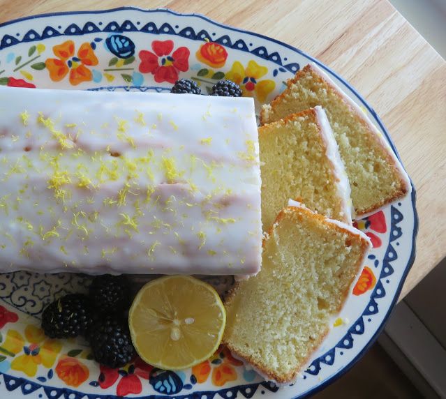 there is a cake with lemons and berries on the plate next to some bread