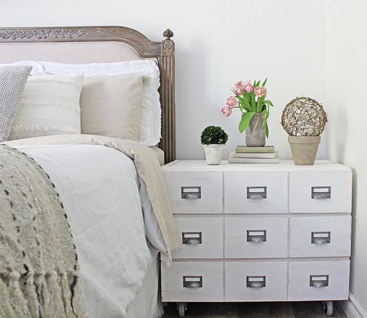 a bedroom with a bed, dresser and flowers on the side table in front of it