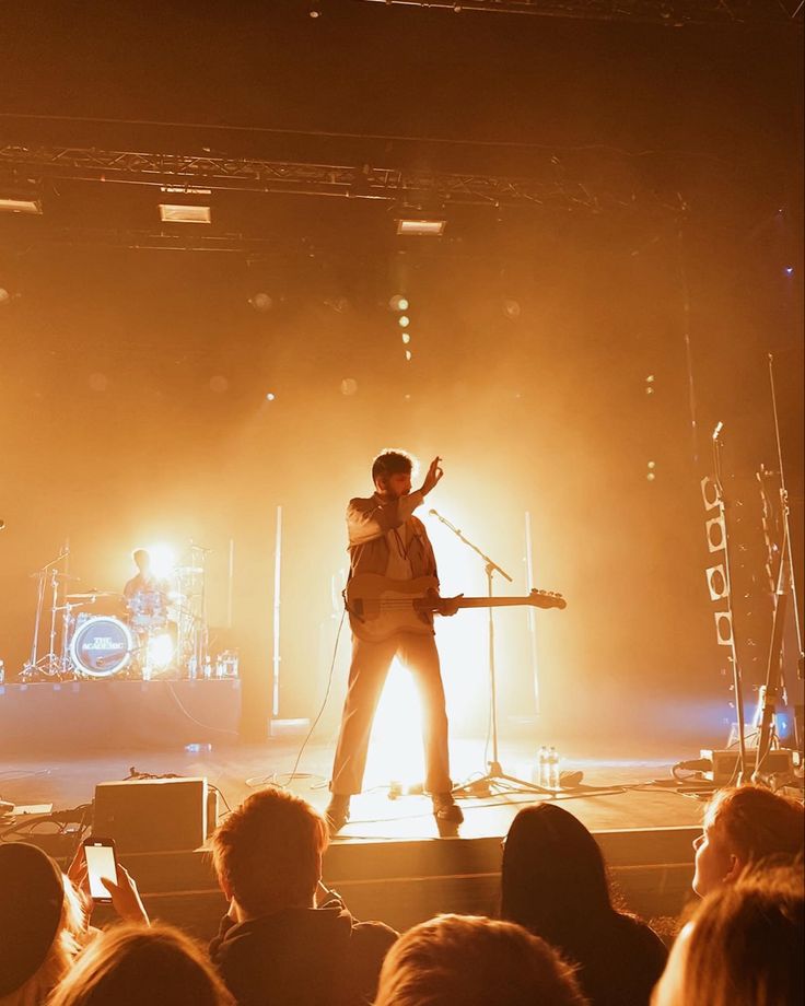 a man standing on top of a stage next to a microphone in front of a crowd