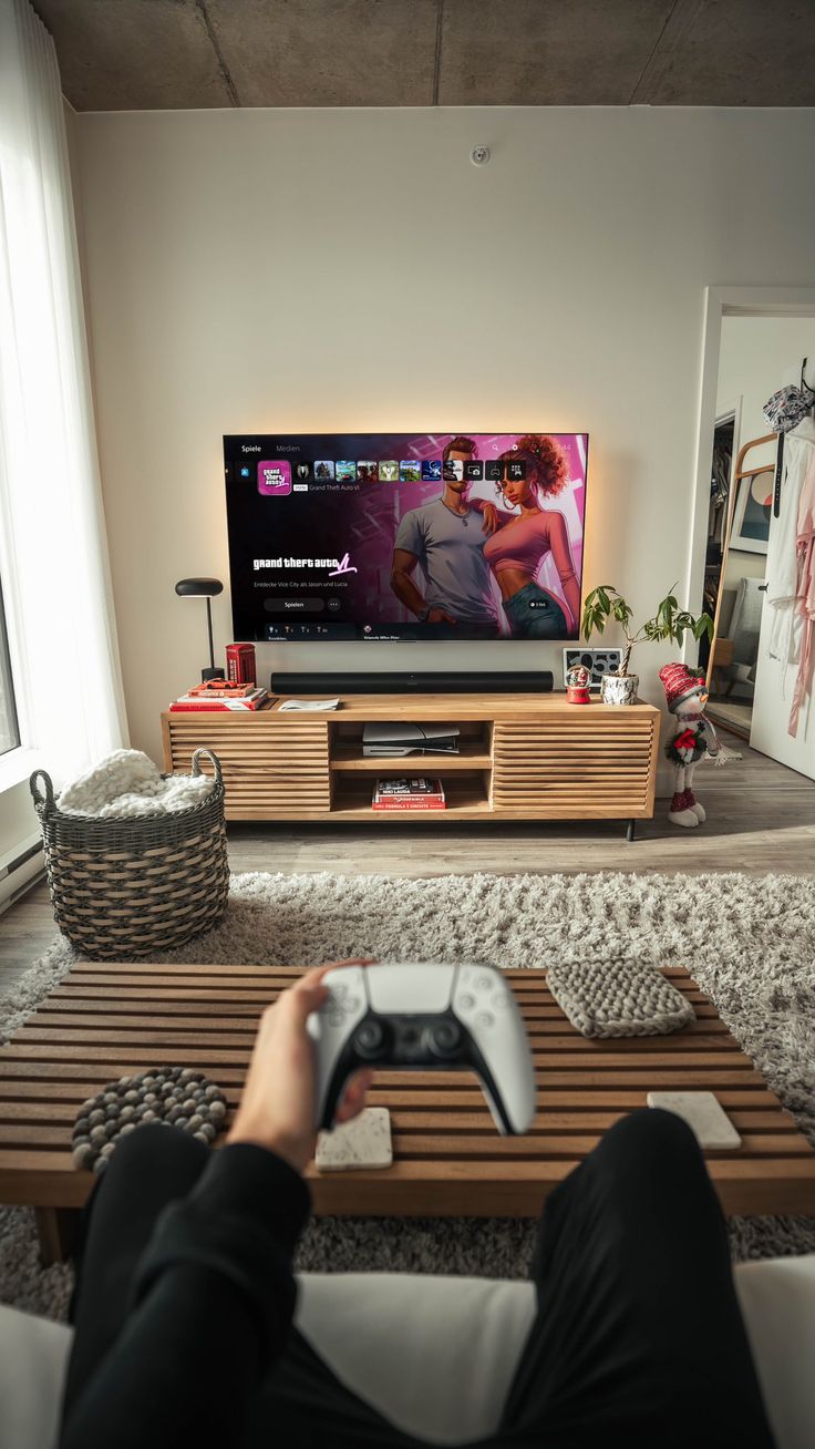 a person sitting on a couch in front of a tv holding a remote control and looking at the television