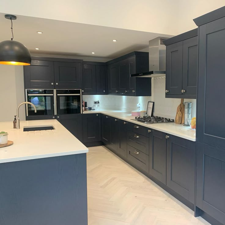 a large kitchen with gray cabinets and white counter tops, an island in the middle