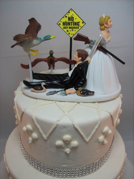 a wedding cake with a bride and groom laying on the ground in front of a no hunting sign