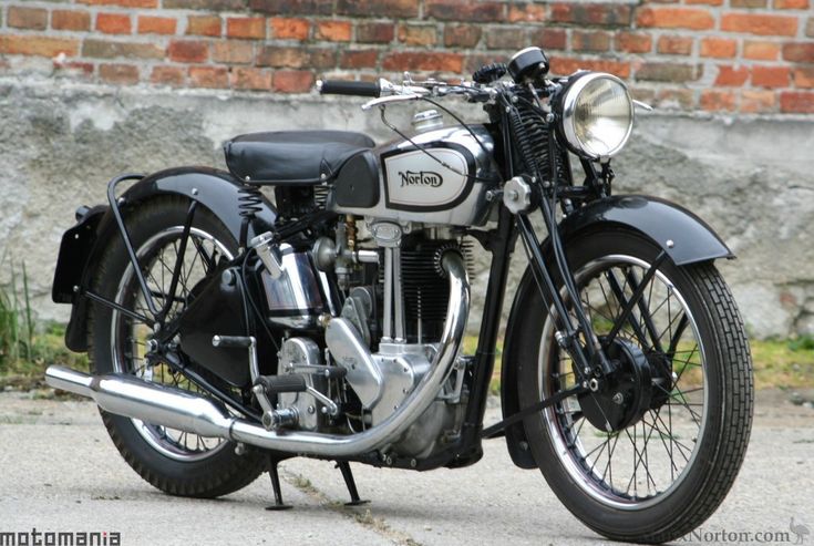 an old fashioned motorcycle parked on the side of the road next to a brick wall