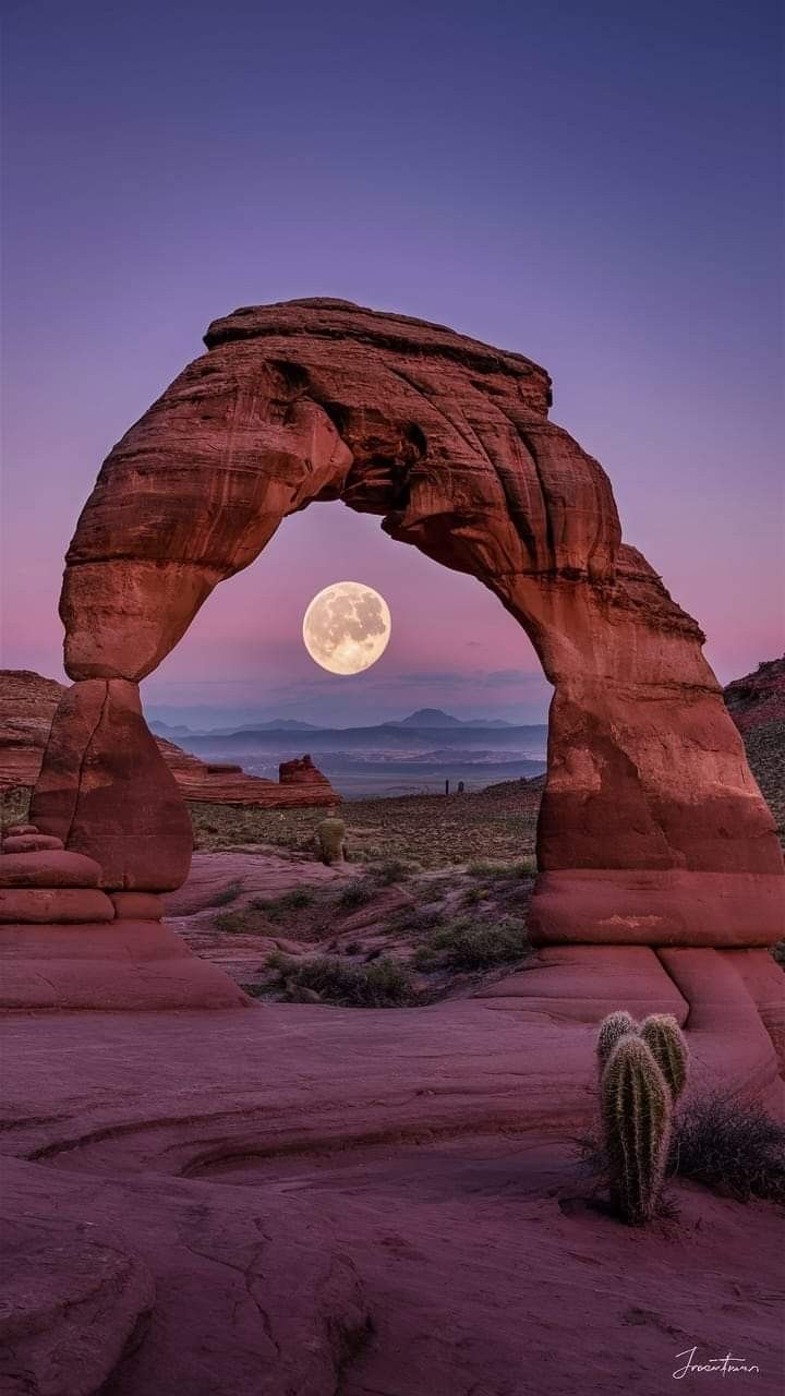 the full moon is seen through an arch shaped rock formation in monument park, utah