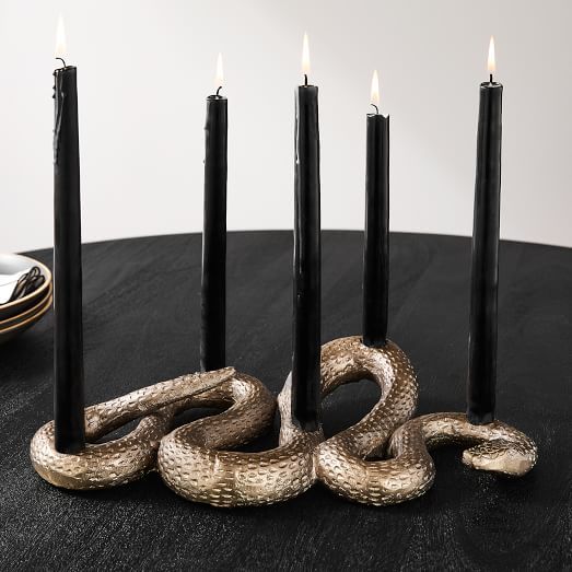 a group of candles sitting on top of a table next to a snake wrapped around them