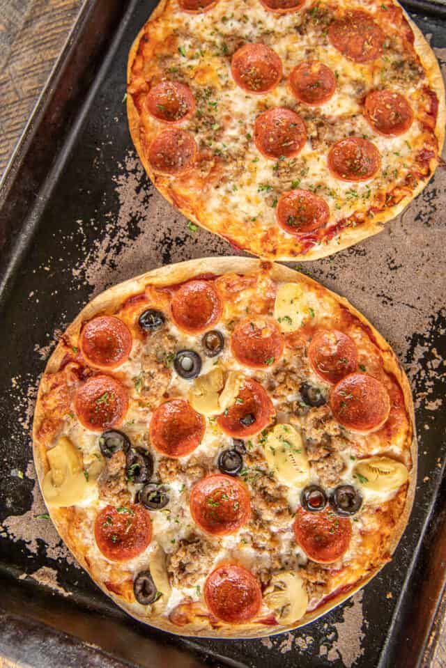 two pizzas sitting on top of a pan covered in cheese and pepperoni toppings