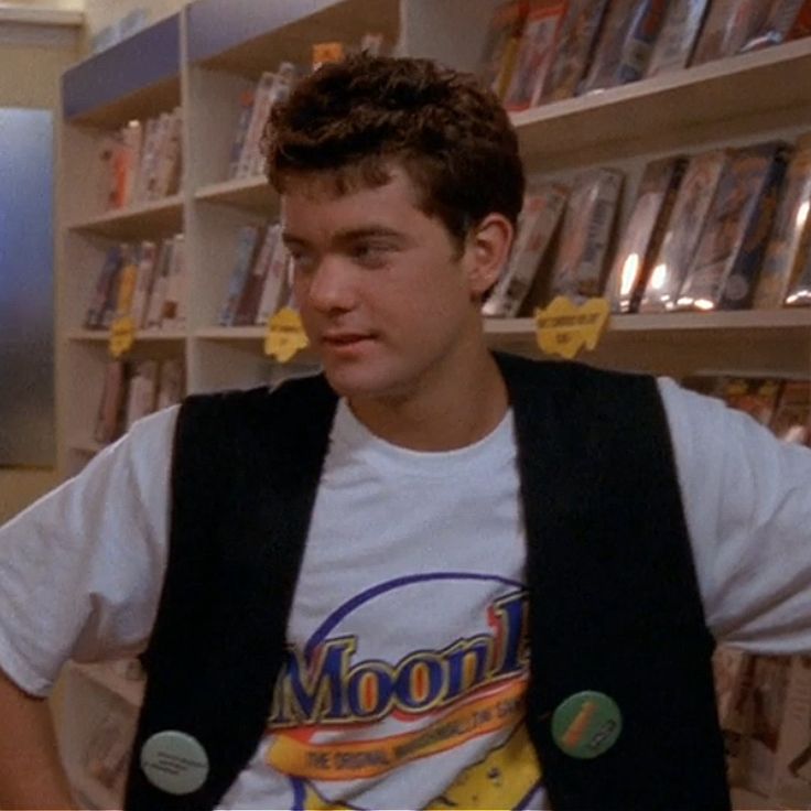 a young man standing in front of a bookshelf