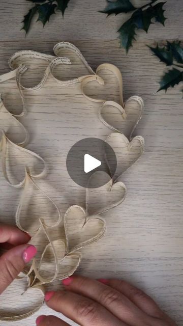 two hands are working on an ornament made out of fabric and paper leaves