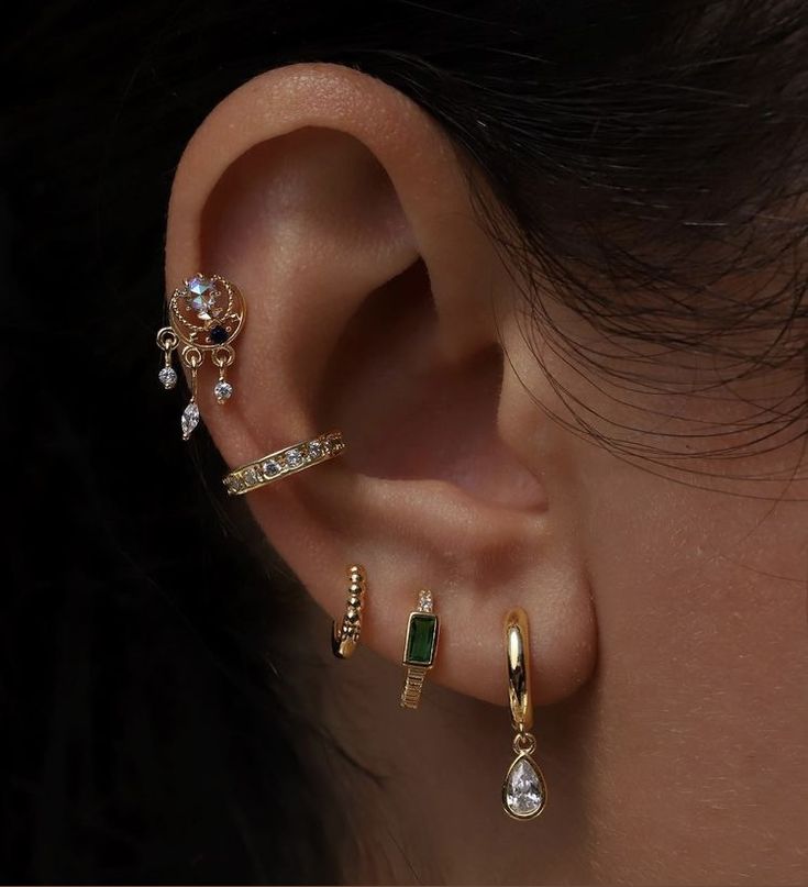 an ear with three different types of piercings on top of it and one is gold