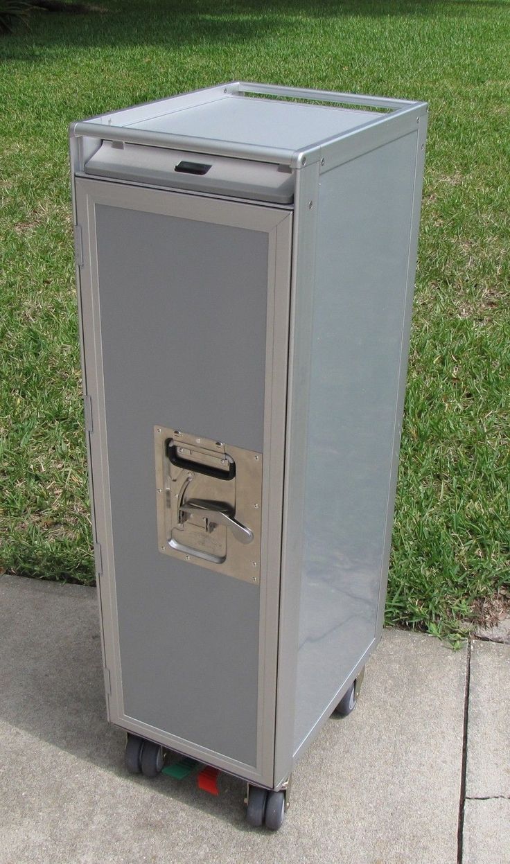 a small gray box sitting on top of a sidewalk next to a grass covered field