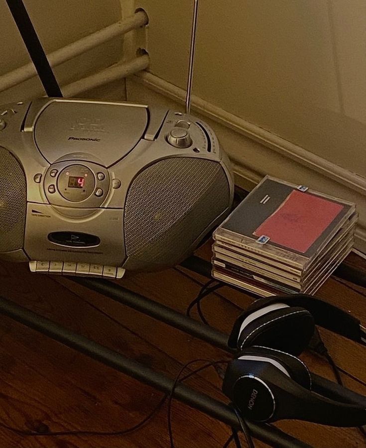 there is a cd player with headphones on the floor next to books and cds