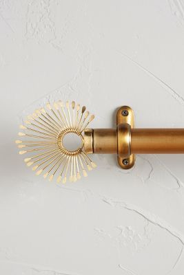 a close up of a gold curtain rod on a white wall