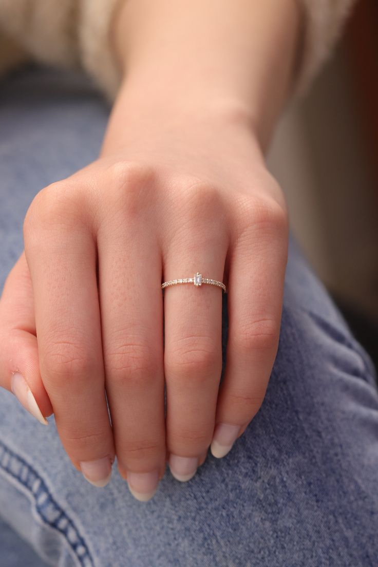 a woman's hand with a diamond ring on her left thumb, sitting down